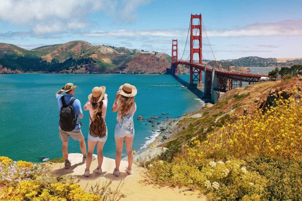 Three people standing on a hill overlooking the ocean.