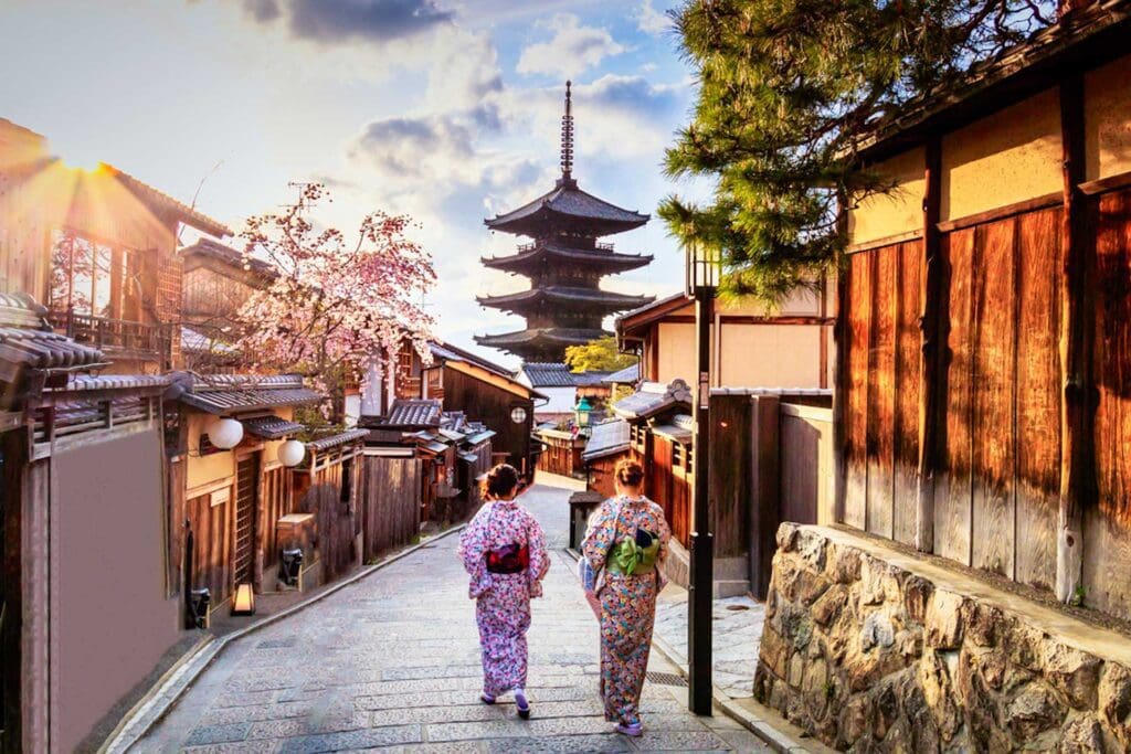 Two women in traditional japanese garb walk down a street.