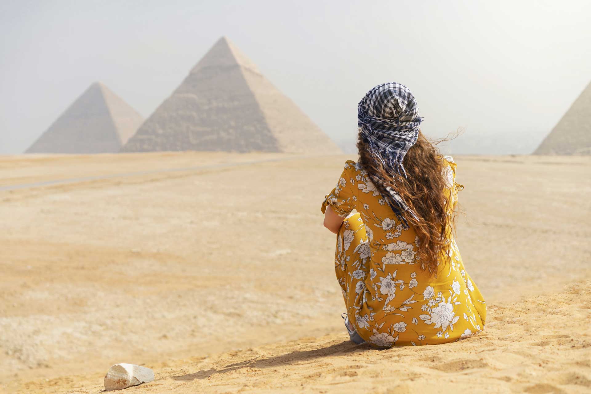 A woman in yellow dress sitting on the ground.