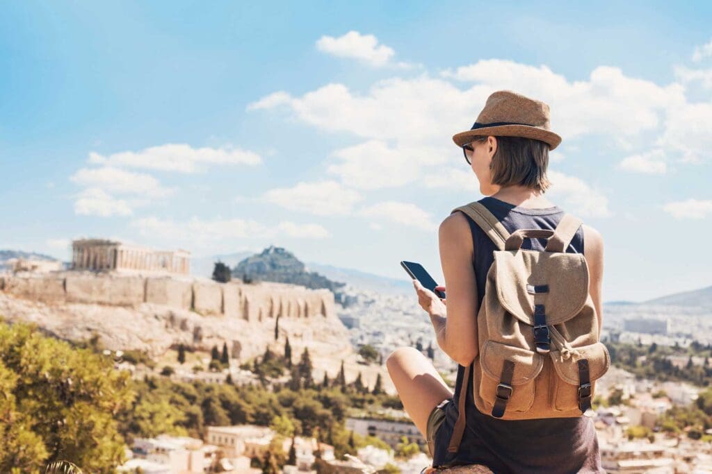 A woman with a backpack and hat looking at the city.