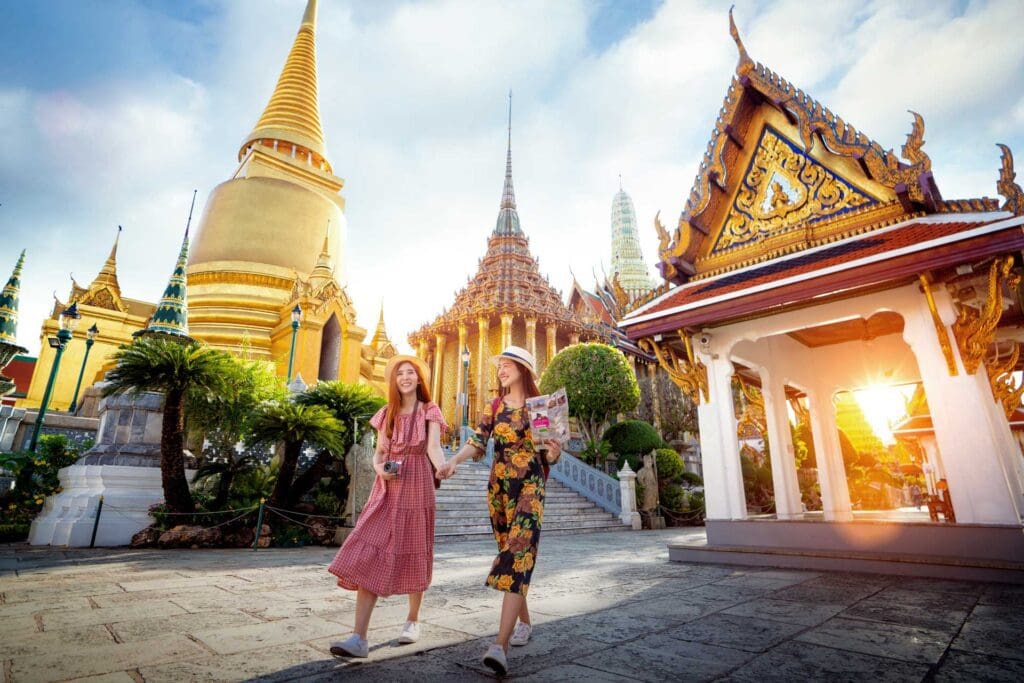 Two women walking in front of a building with many spires.