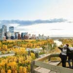 Two people taking pictures of a city skyline.