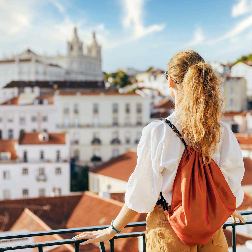 A woman standing on the balcony of her home looking at the city.