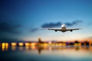 A large jetliner flying over water at dusk.