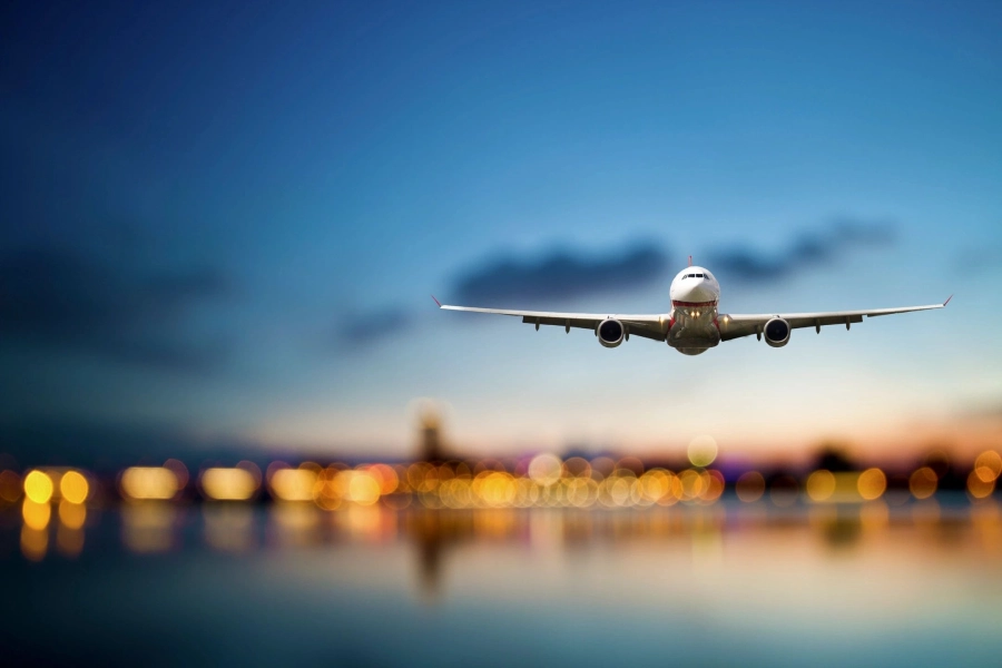 A large jetliner flying over water at dusk.