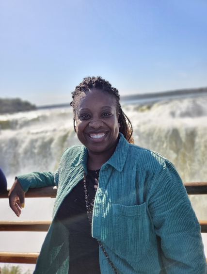 A woman standing in front of a waterfall.