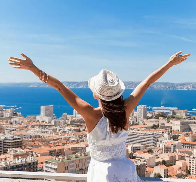 A woman in white shirt and hat with arms raised.