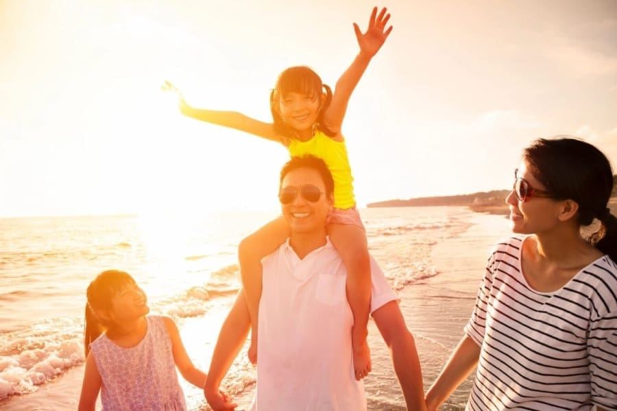 A family is walking along the beach at sunset.