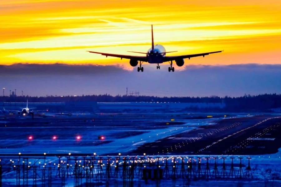 A plane flying low over an airport runway.