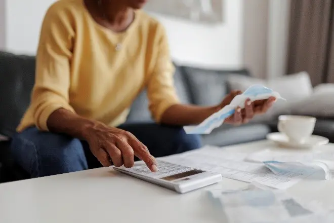 A person sitting at a table with papers and a calculator.